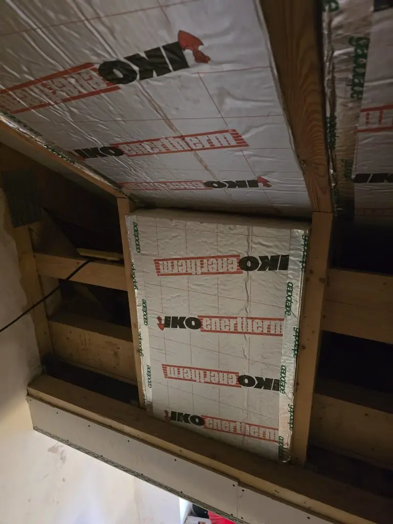 PIR boards wedged between rafters, fitted so that they can be taken out later.