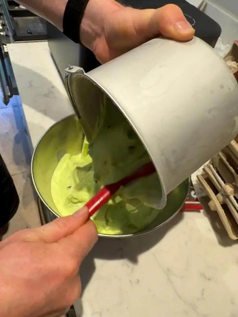 Churned mint choc chip ice cream scraped from the canister into a metal bowl