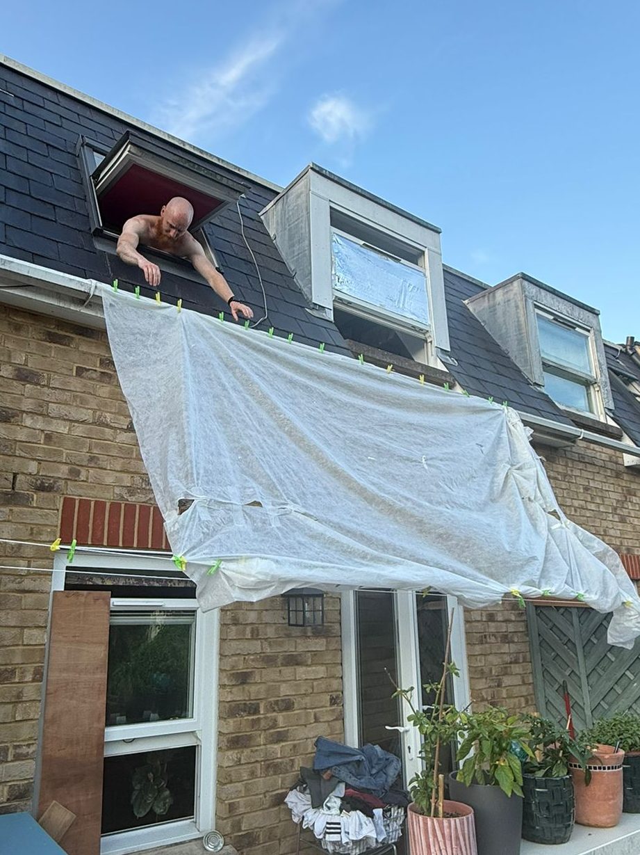 A white sheet hung from an upstairs dormer window down over the ground-floor patio doors as a makeshift awning.