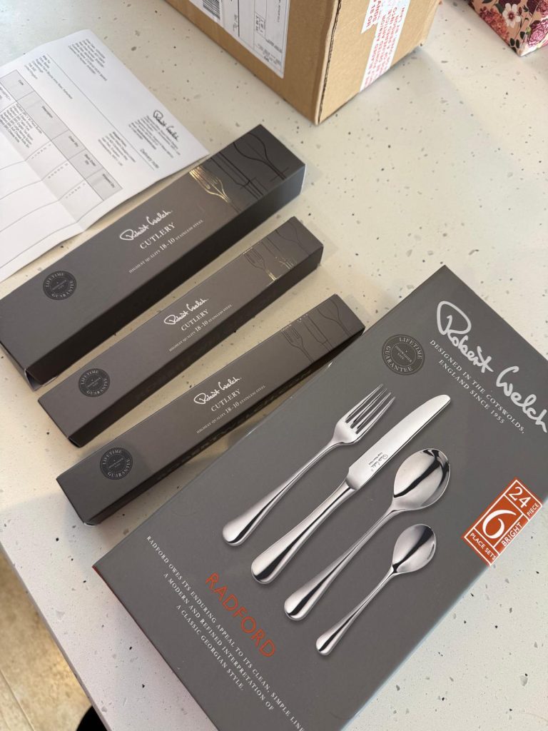 Boxes of Robert Welch Radford Bright cutlery on a worktop, one showing a place setting on the front.