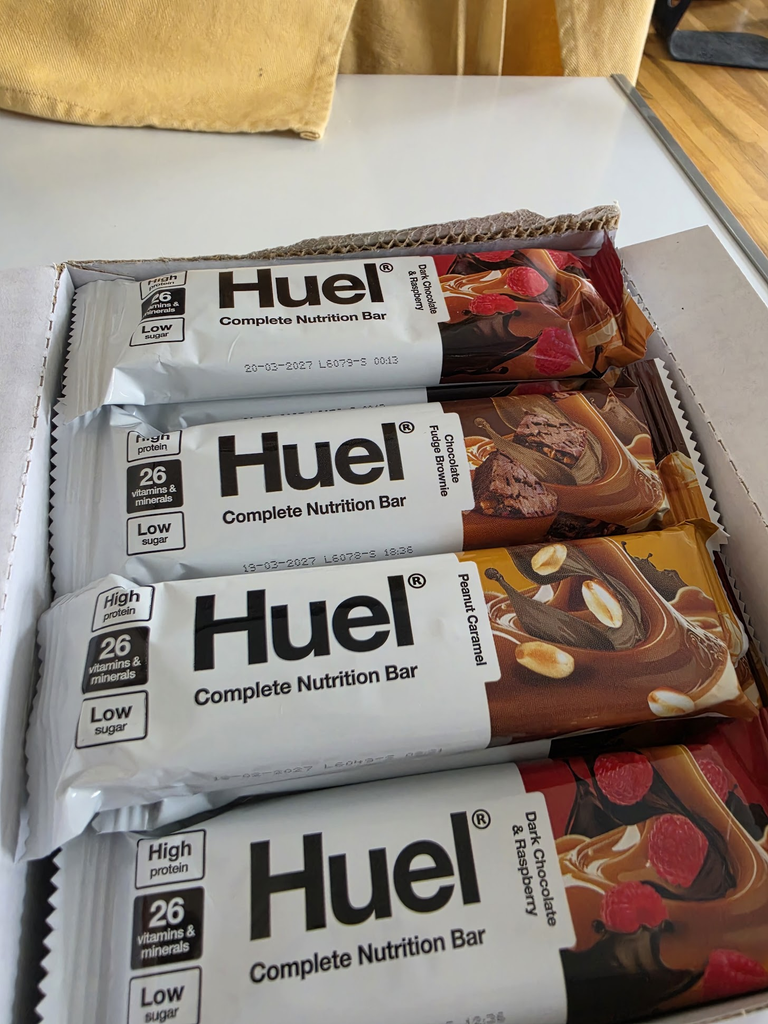 Four Huel Complete Nutrition Bars in different flavours laid out on a table.